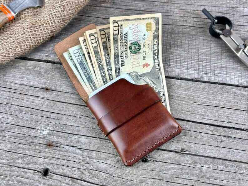 Minimalist genuine leather wallet featuring cash and cards on a rustic wooden surface.
