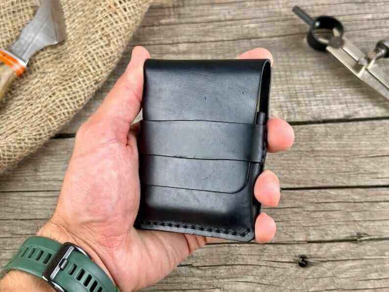 A hand holding a minimalist genuine leather wallet, showcasing its sleek design and premium material.