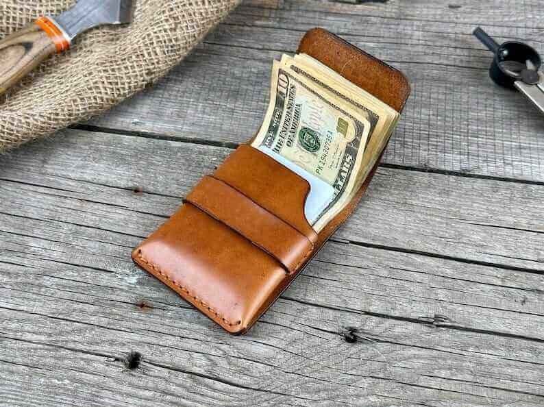 Minimalist genuine leather wallet showcasing cash and cards on rustic wooden surface.