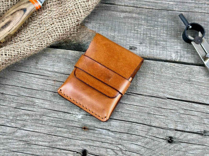 Minimalist genuine leather wallet displayed on rustic wooden surface with tools in background.