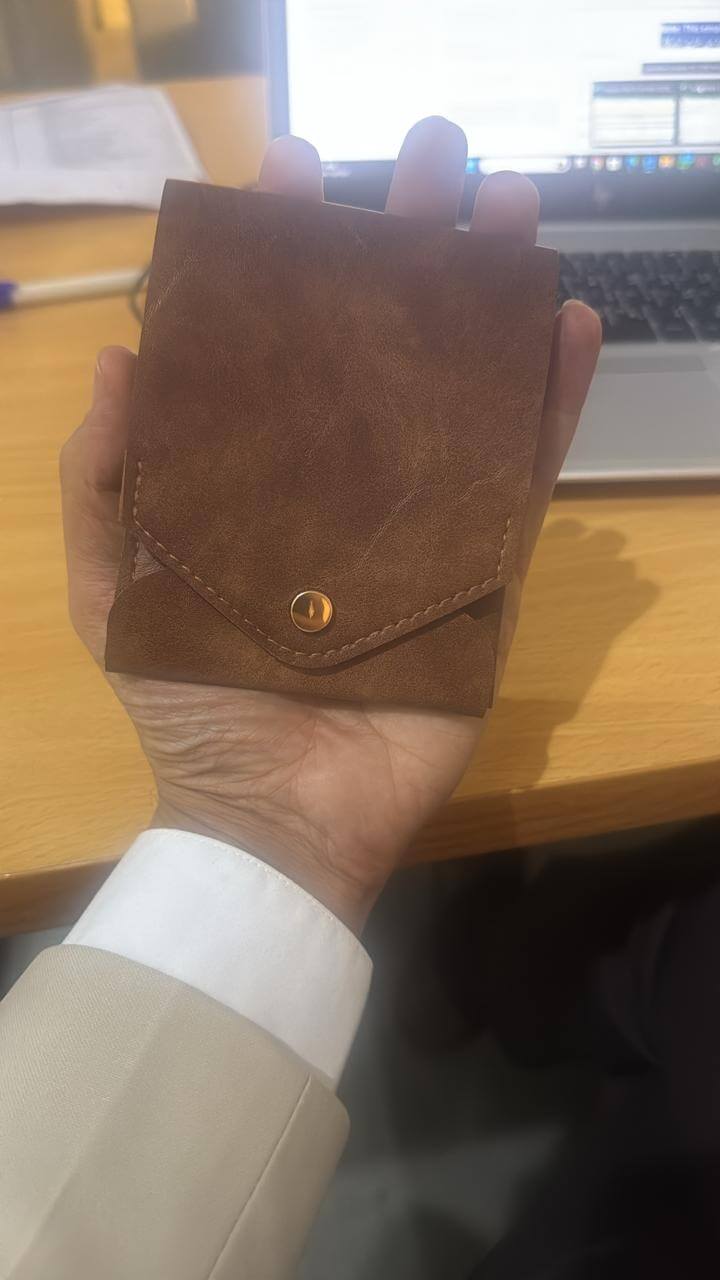compact leather wallet with pen in hand, showcasing premium craftsmanship and practical design.