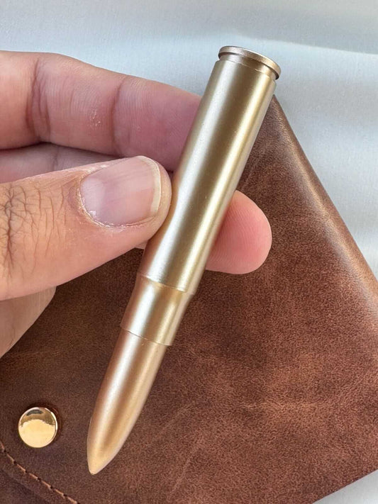 compact leather wallet with pen: Close-up of a sleek gold pen held above a brown leather wallet.