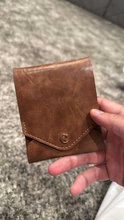Compact leather wallet with pen: Pathfinder held in hand, showcasing its premium leather and sleek design.