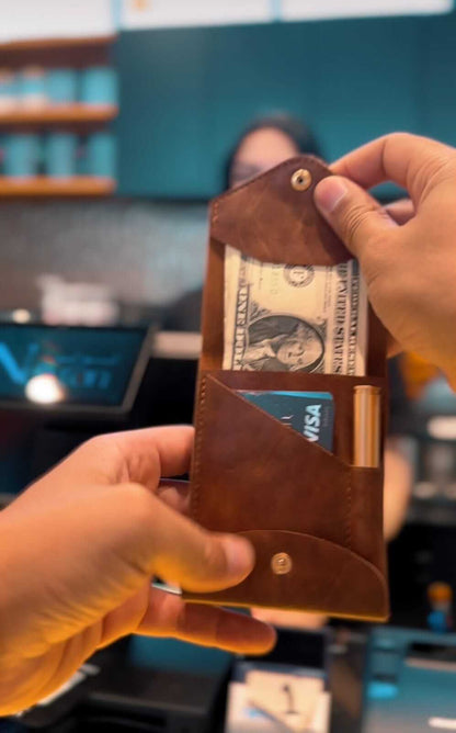 compact leather wallet with pen: Pathfinder showing cash and card slots being held in hand.